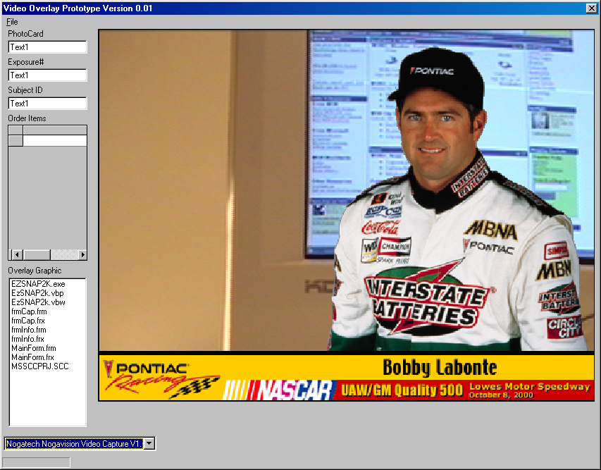 The Video Overlay Prototype Version 0.01 application window — live video composited in real time behind a cutout of NASCAR driver Bobby Labonte in his Interstate Batteries fire suit, above a Pontiac Racing / NASCAR / UAW-GM Quality 500 Lowe's Motor Speedway banner dated October 8, 2000. PhotoCard, Exposure#, and Subject ID fields and an Order Items grid sit at left; the Nogatech Nogavision capture driver is selected below. The only known screenshot of the ISA Event Photo System running.