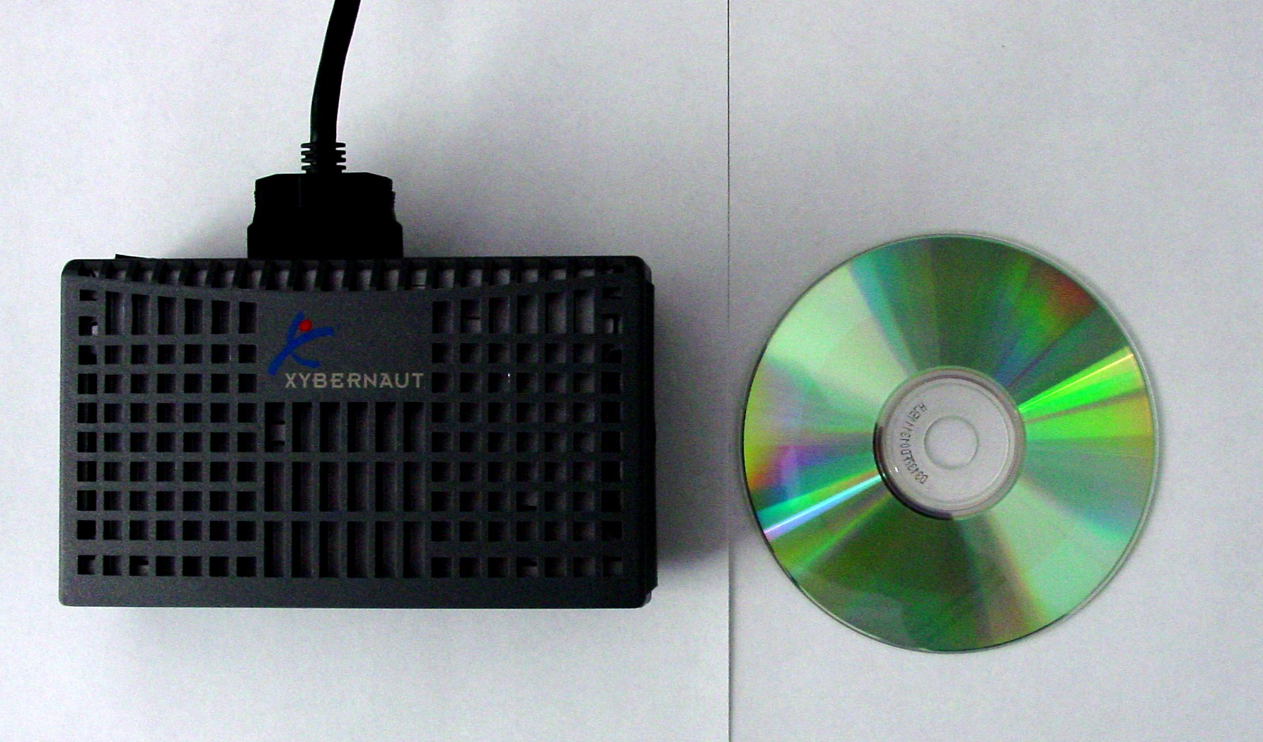 Xybernaut MA-V wearable PC photographed next to a CD for size reference — A1SI's own period photograph of the actual hardware the developer worked with on the ISA Event Photo System project. Fitting a Pentium-class Windows machine into a paperback-book-sized case was the leading edge of commercial wearable computing in 2001.